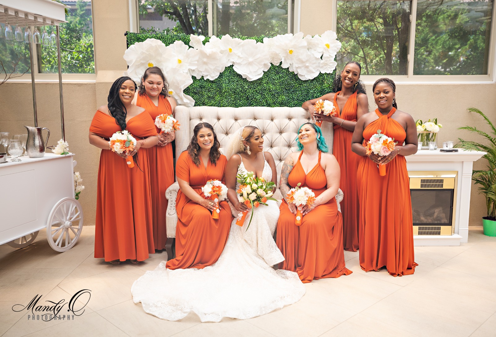 A group of women in orange infinity dress, with roses in hands.