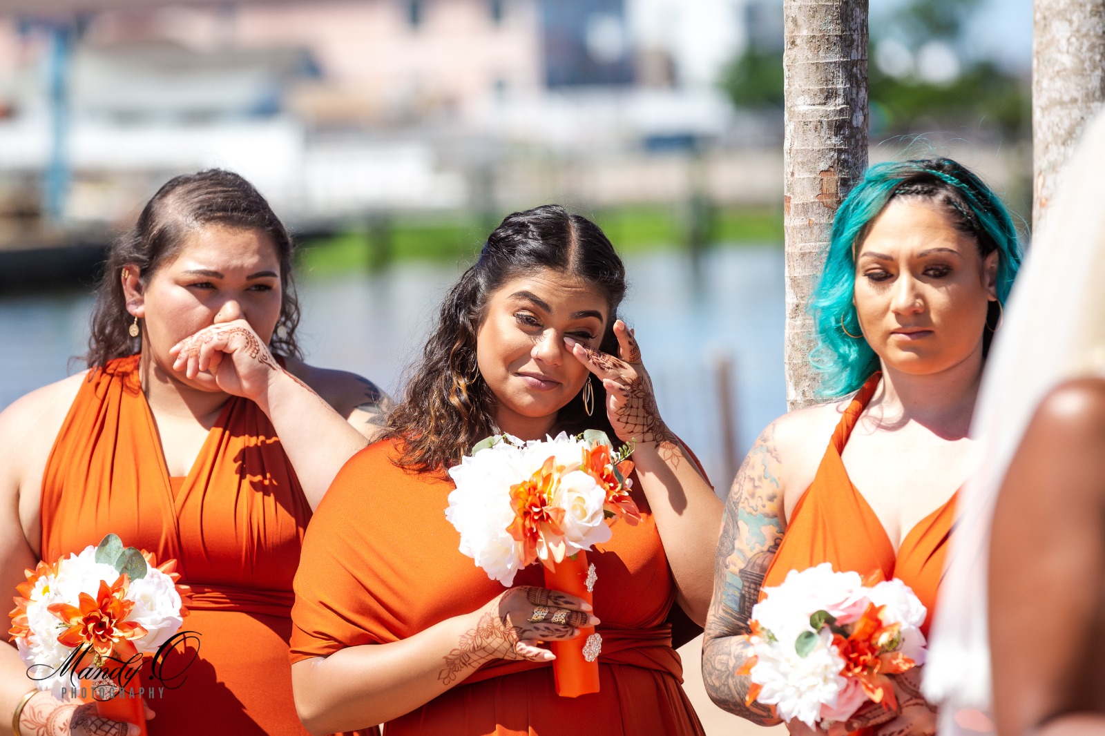 women in rust bridesmaid dresses with roses in hands.